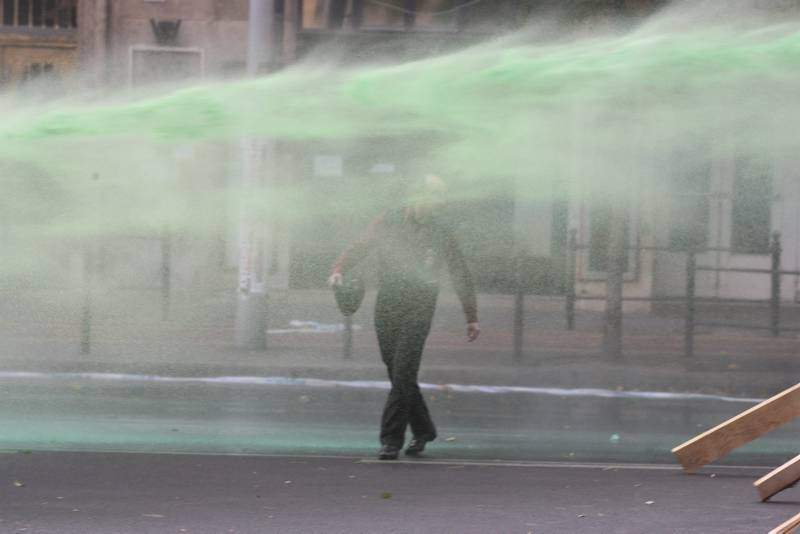 Water cannon spraying green dye over a protester
